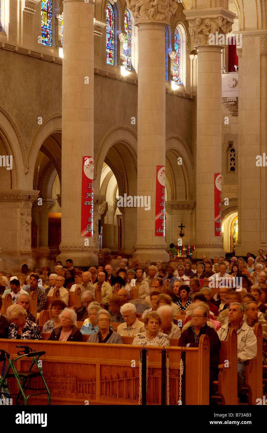 People sitting waiting for mass inside the cathedral at Ste Ane de Beaupre in Quebec Stock Photo