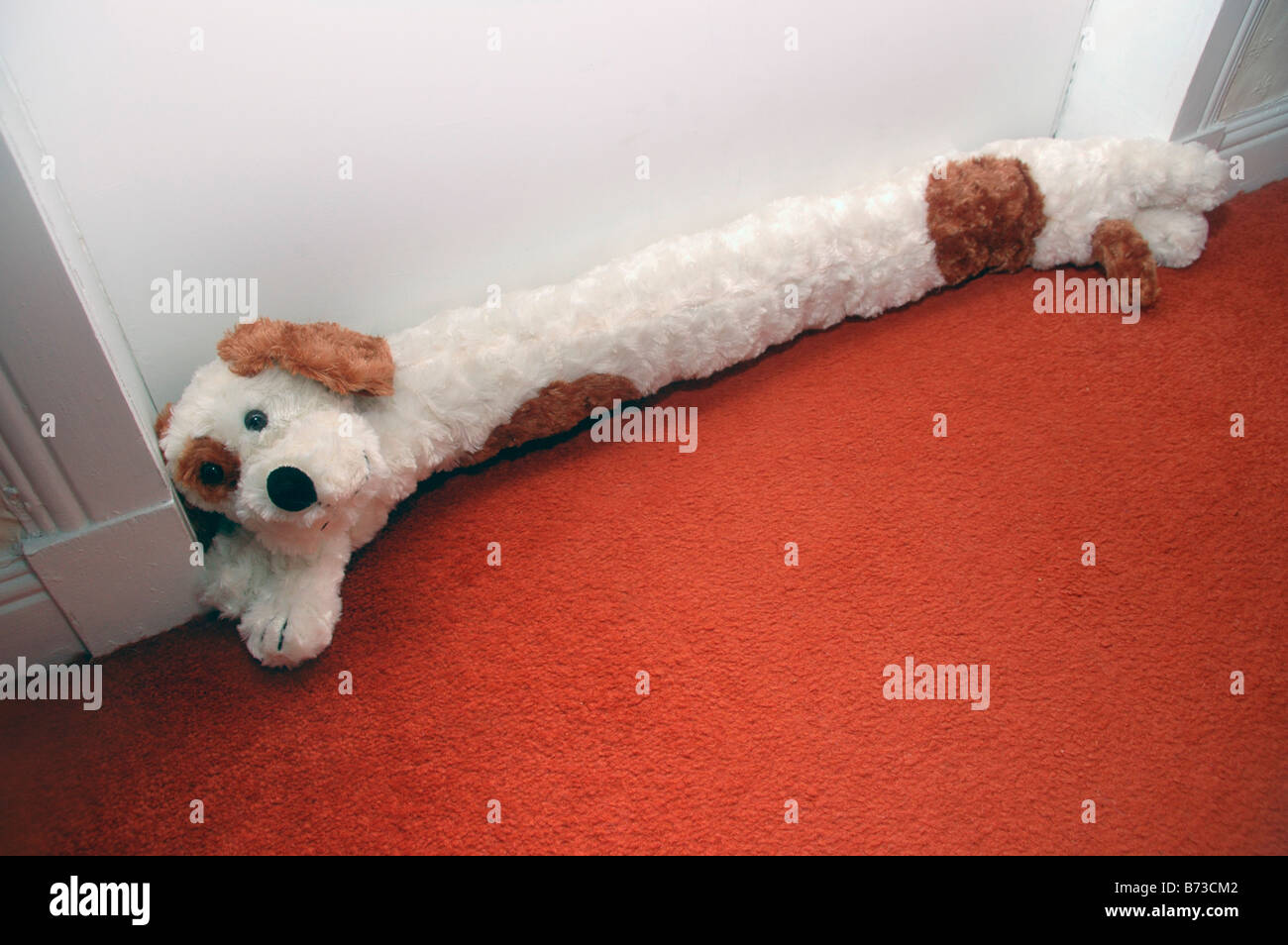A dog shaped draft excluder lies at the base of a door Stock Photo Alamy