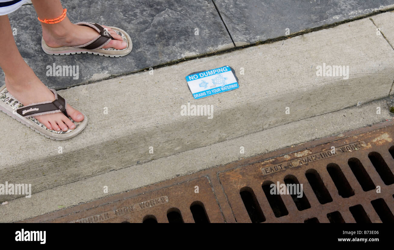 Storm drain with decal warning against pollution dumping Stock Photo