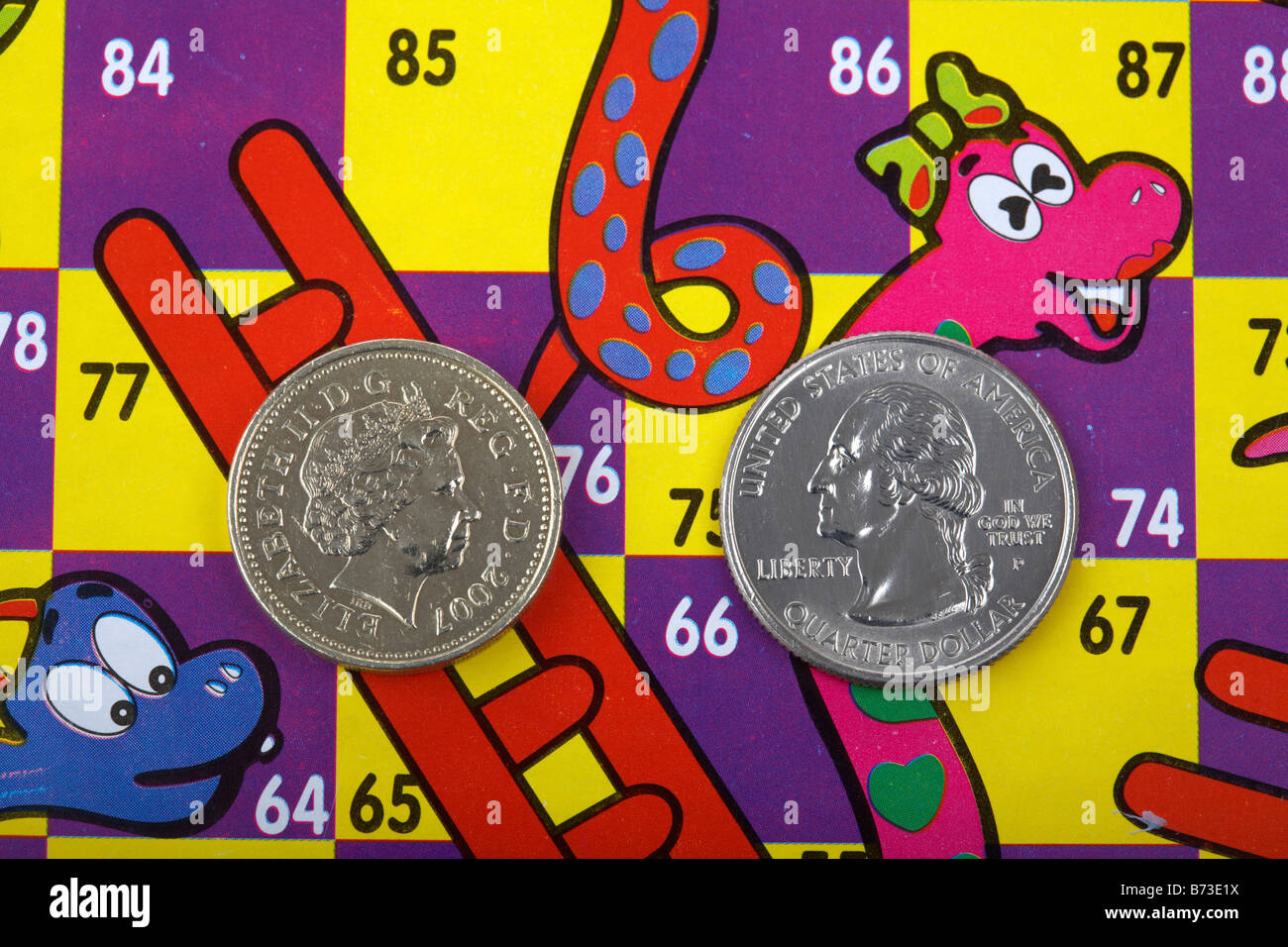 one us quarter dollar 25c coin and pound coin on a snakes and ladders board with pound on the ladder and quarter on the snake Stock Photo