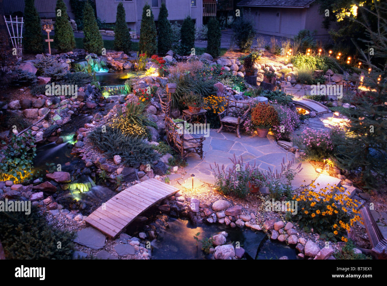 PATIO OF NATURAL STONE AMID GARDEN OF PERENNIALS, BRIDGES AND A FLOWING