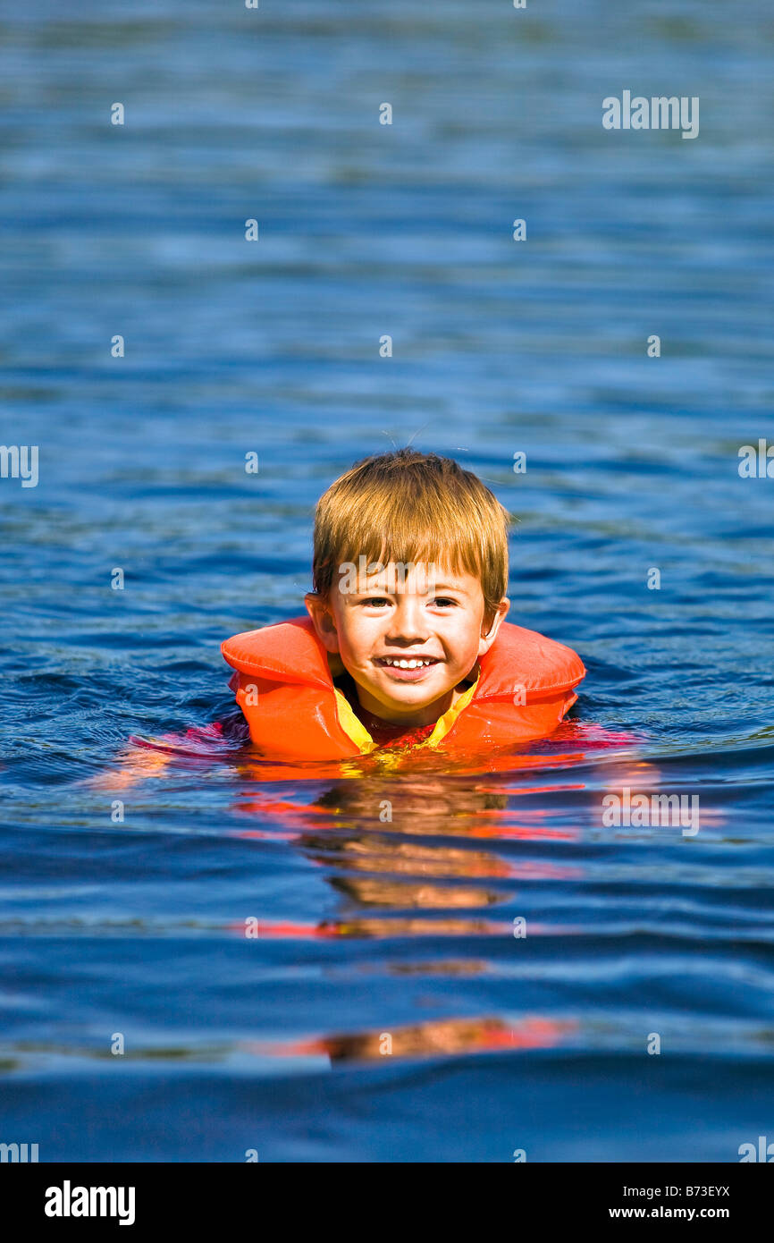 Young boy learning to swim in lake, wearing a life jacket Stock Photo