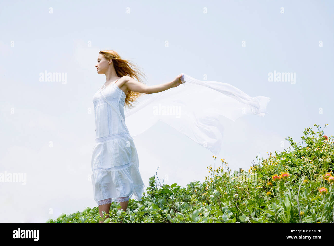 Young woman standing holding out shawl in wind Stock Photo