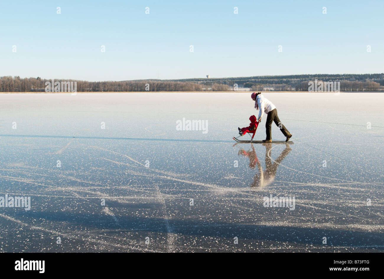 Mother and child having fun on lake ice with a traditional nordic kicksled, Lohja, southern Finland Stock Photo