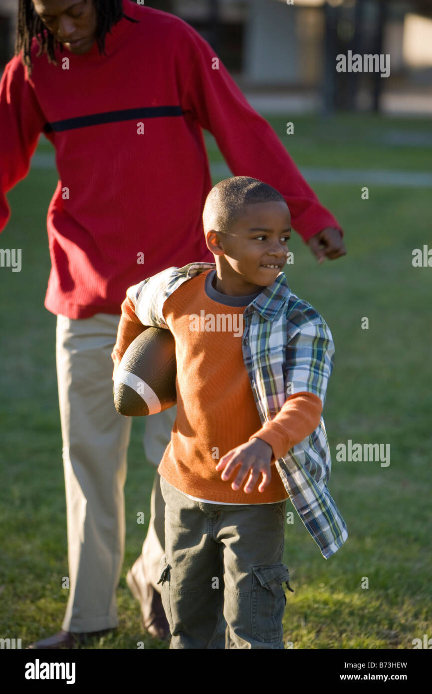 African American father and son playing football in park Stock Photo ...