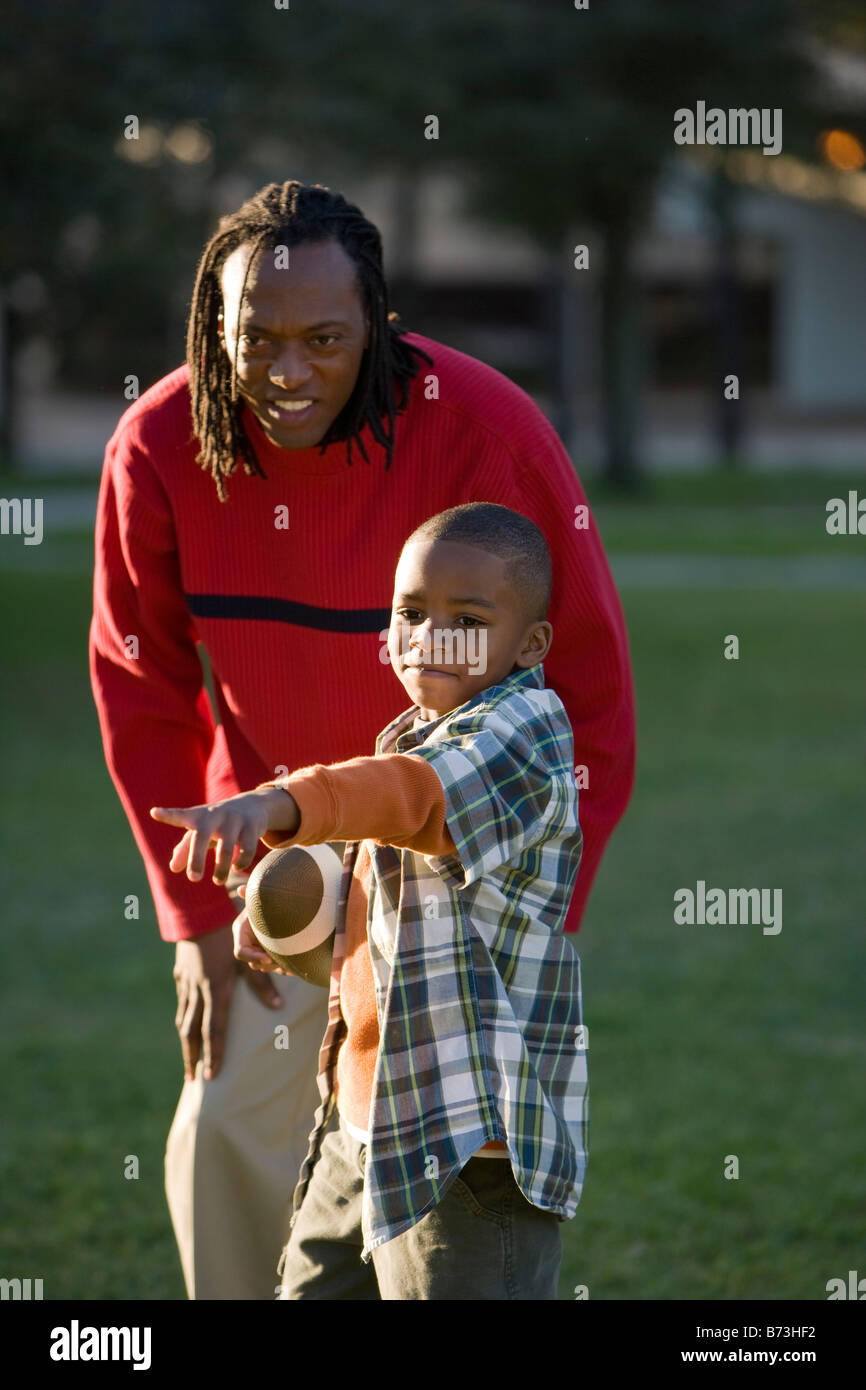 African American father and son playing football in park Stock Photo ...