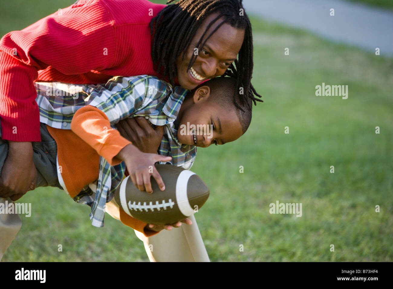 African American father and son playing football in park Stock Photo ...