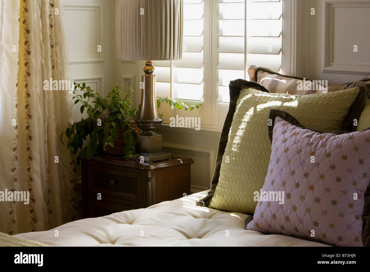 Purple and green decorative pillows on bed near window Stock Photo Alamy