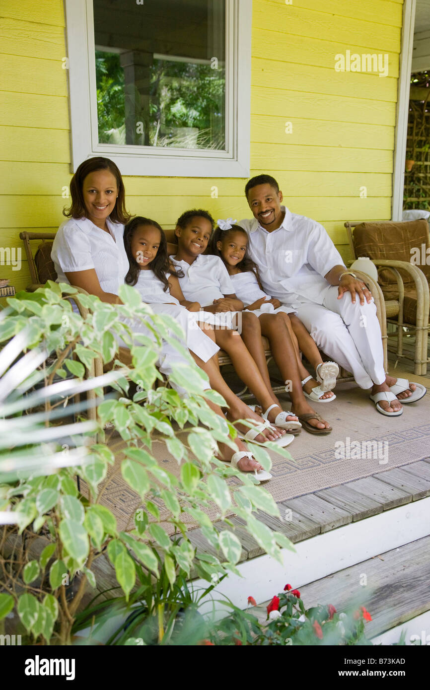 Happy African American family sitting on bench on front porch of house