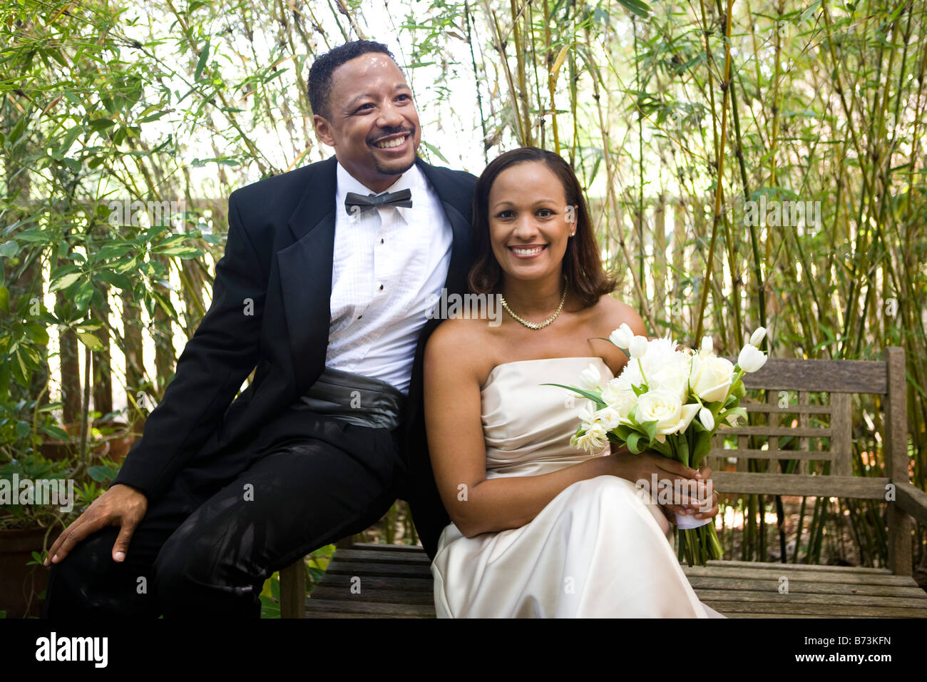 Happy African-American bride and groom sitting on bench Stock Photo - Alamy