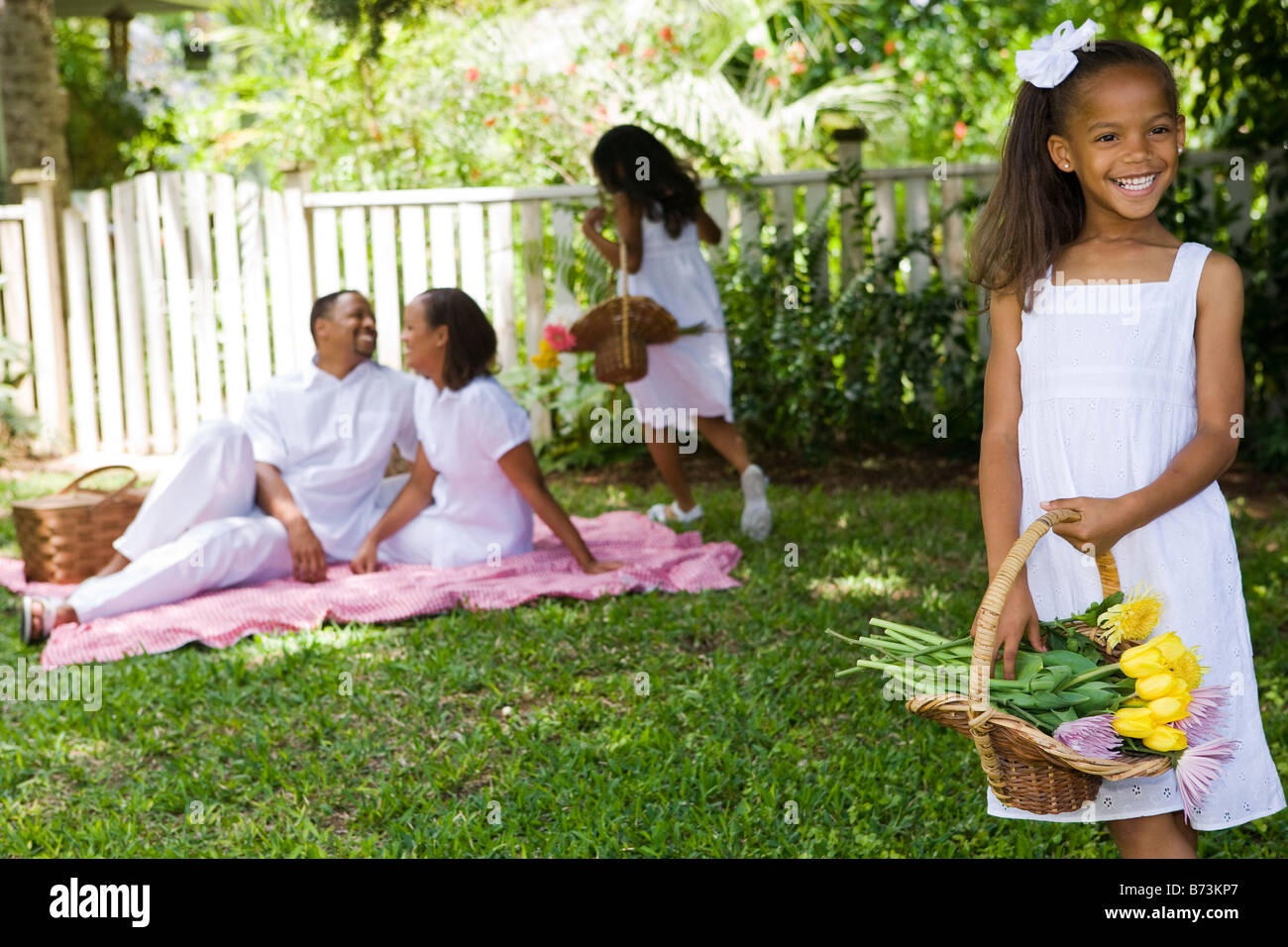 AfricanAmerican girl holding flower basket, family picnic in background Stock Photo Alamy