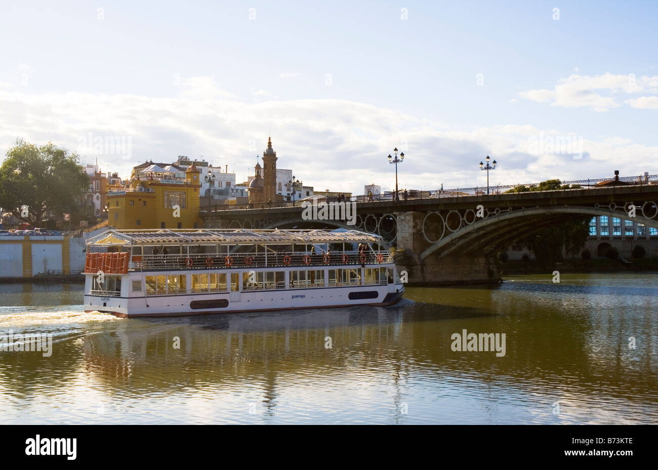 Seville Spain Excursion boat sailing under the Puente de Triana or Puente de Isabell II on the river Guadalquivir Stock Photo