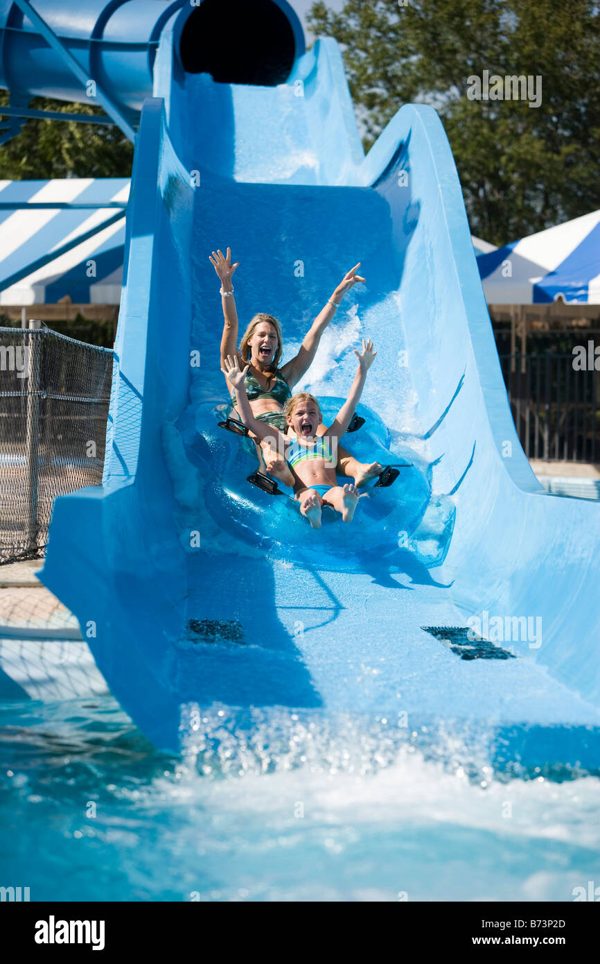 Mother and daughter sliding on water slide in water park Stock Photo