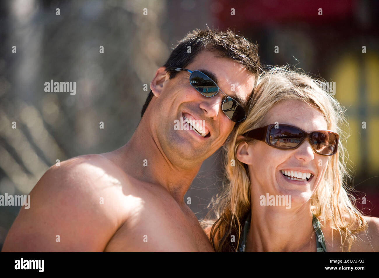 Close-up of grinning mid-adult couple in swimsuits and sunglasses on sunny day Stock Photo
