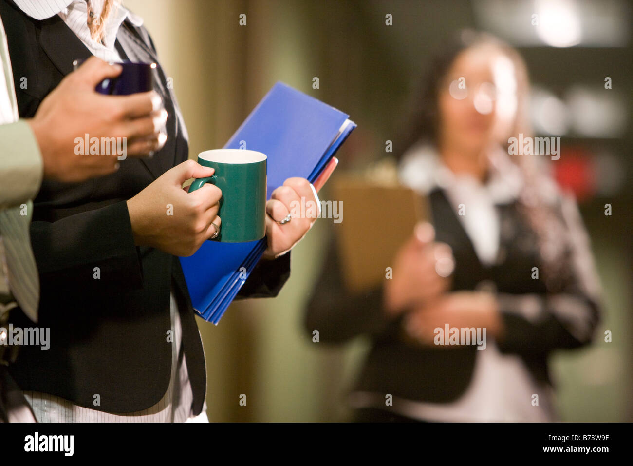 Midsection of office workers taking coffee break in hallway Stock Photo