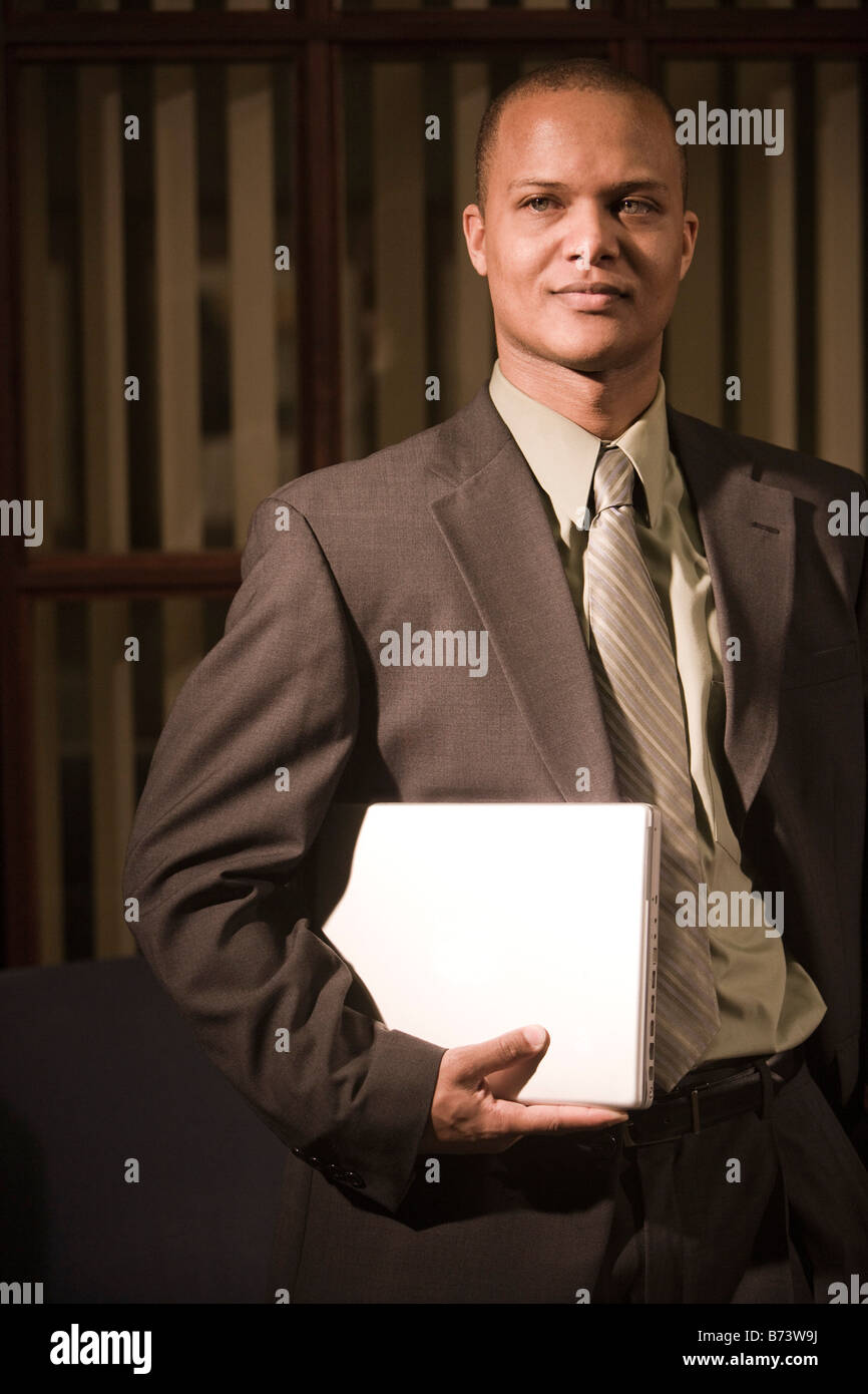 Young African-American businessman holding laptop in office Stock Photo ...