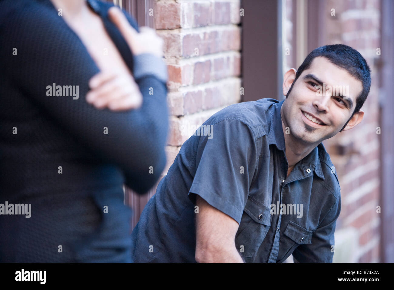 Young Hispanic man sitting on stoop looking up at girlfriend Stock ...