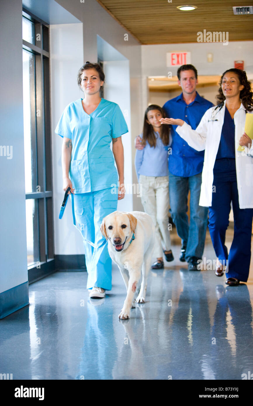 Veterinarian walking with family and dog down clinic corridor