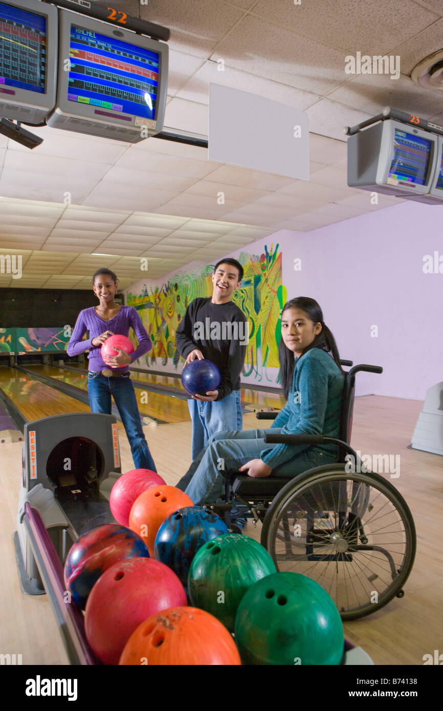Multi-racial teenagers and girl in wheelchair at bowling alley Stock Photo