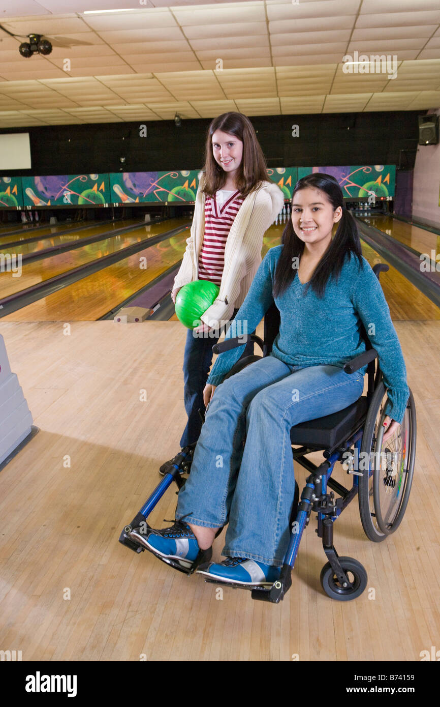 Teenage girl in wheelchair with friend in bowling alley