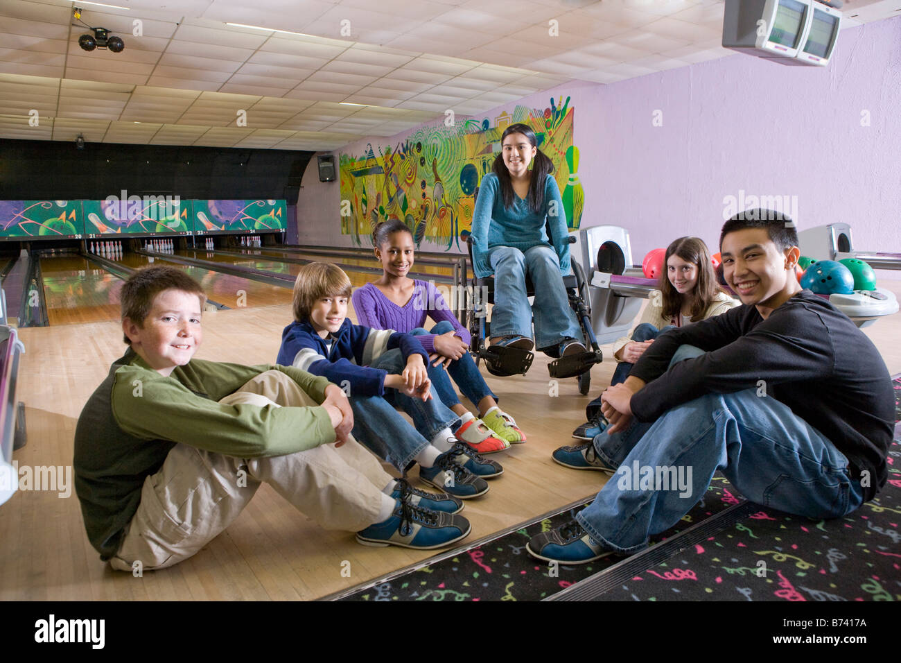 Group of multiracial children with girl in wheelchair in bowling alley Stock Photo