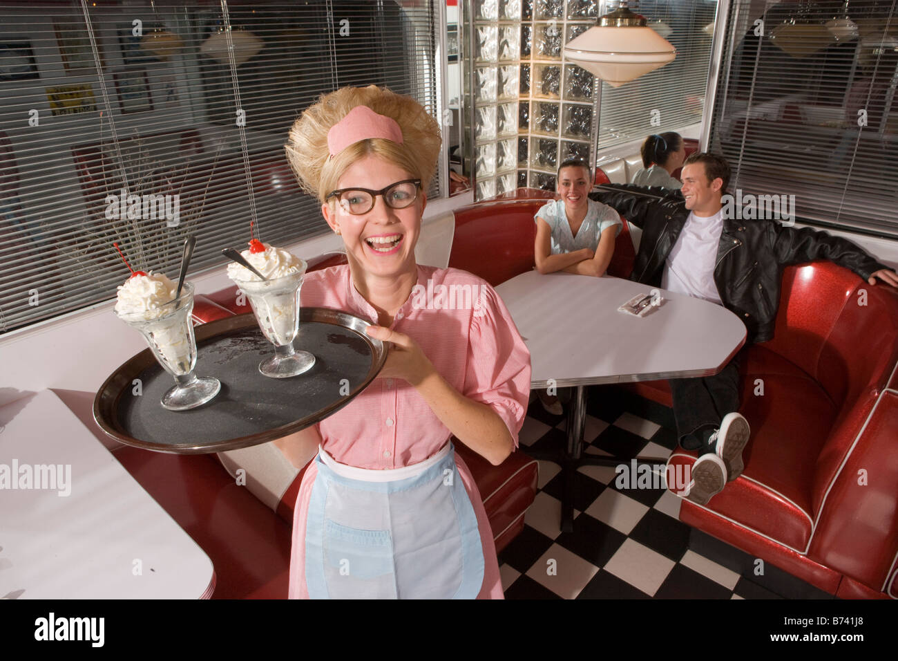Happy waitress in 1950s style uniform serving ice cream 