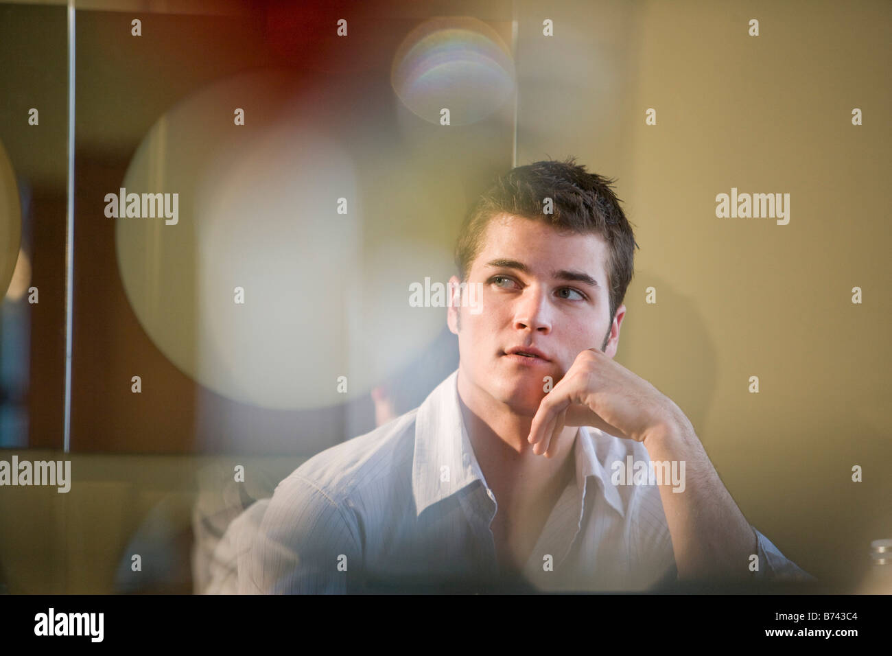 Young man with hand resting on chin Stock Photo - Alamy