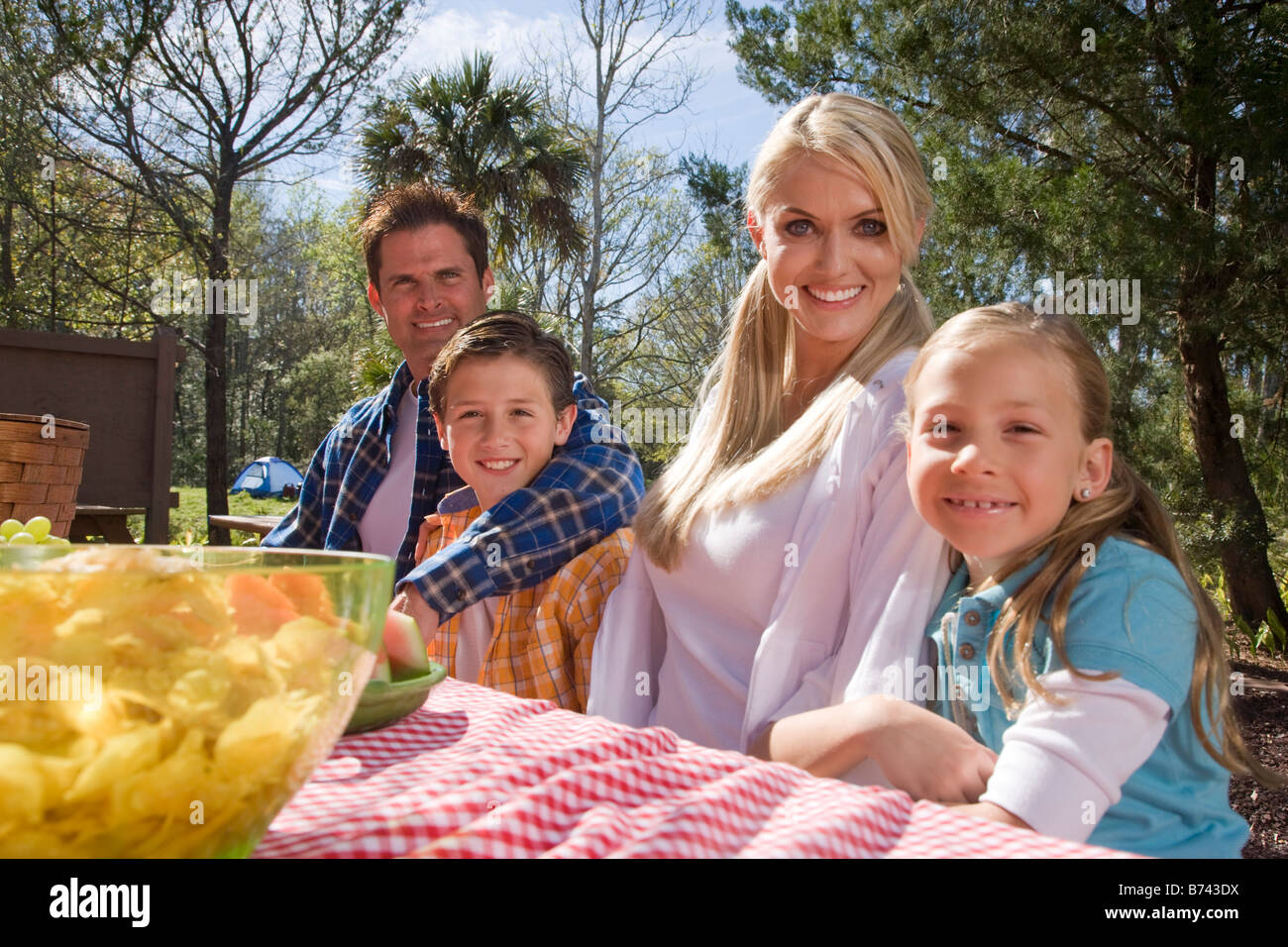 Young happy family sitting at picnic table near campsite Stock Photo
