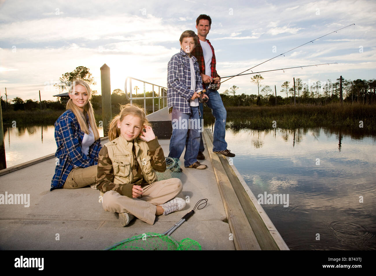 Young happy family fishing by river Stock Photo - Alamy