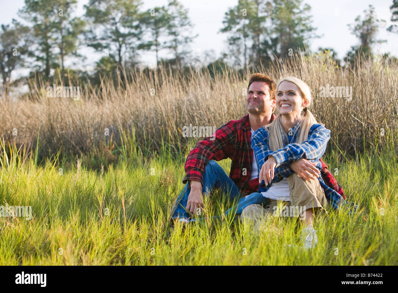 Couple sitting on grass in outdoor clothing Stock Photo