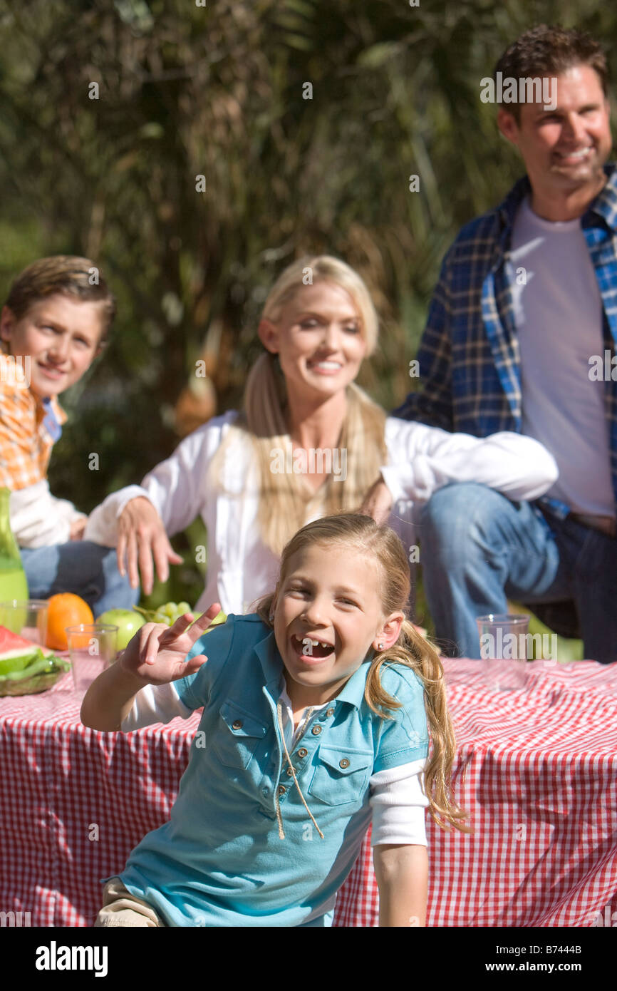 Young girl having fun at picnic table with family in background Stock Photo