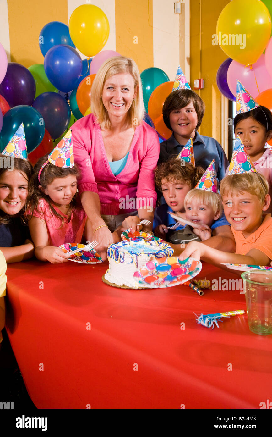 Mother cutting birthday cake at birthday party Stock Photo