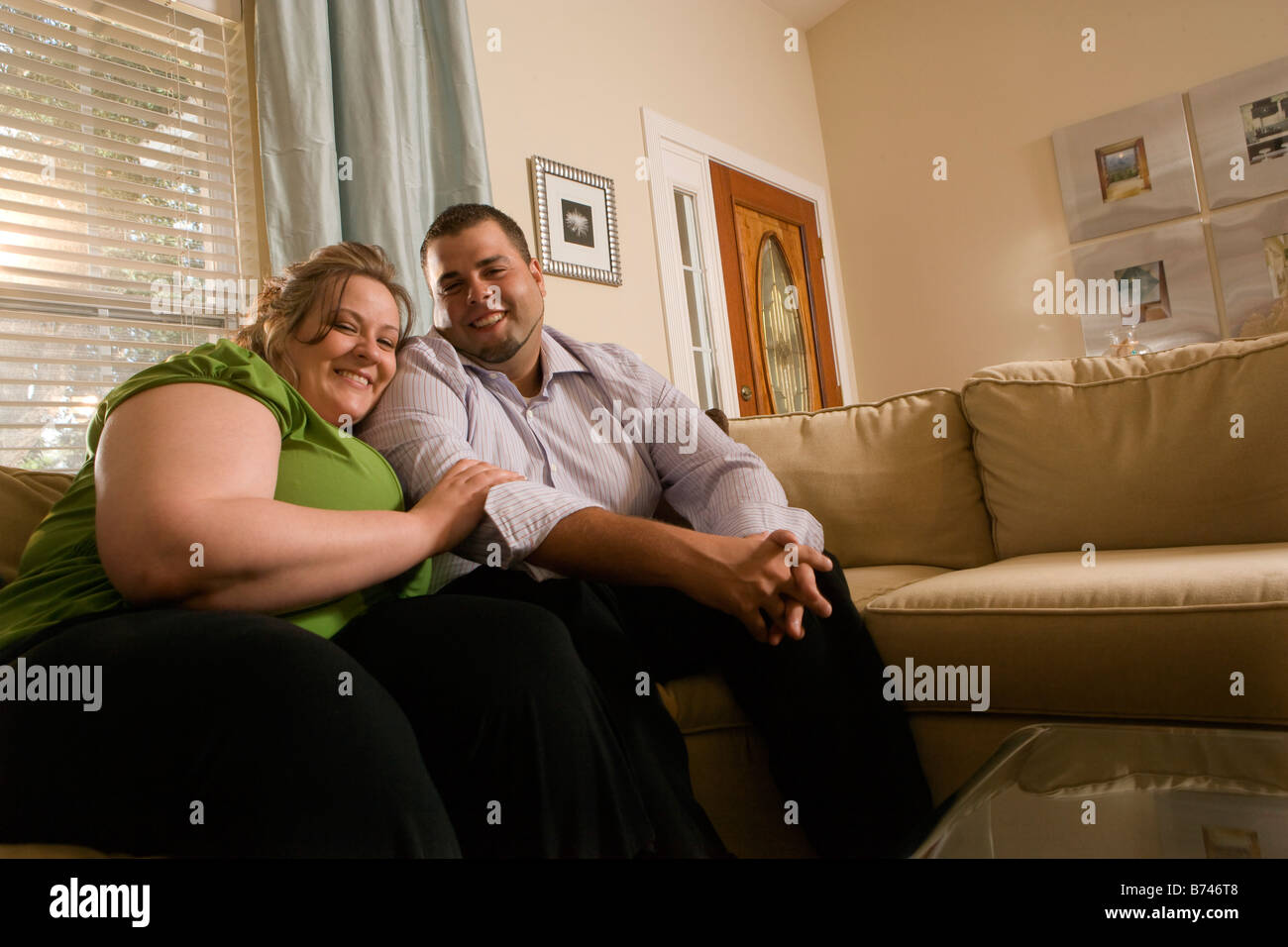 Overweight couple sitting on sofa in living room Stock Photo Alamy