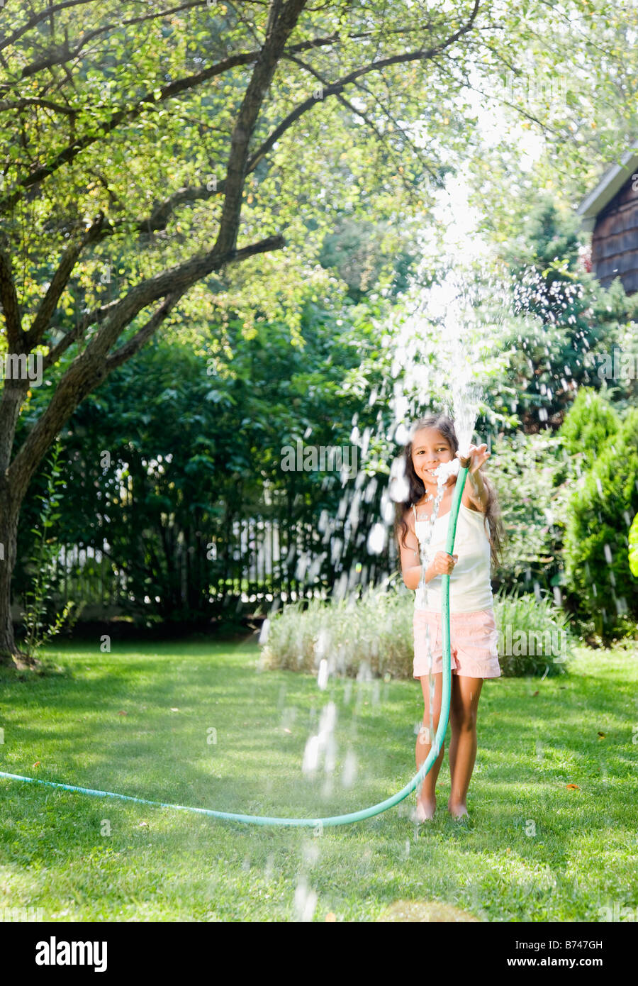 Hispanic girl squirting hose Stock Photo