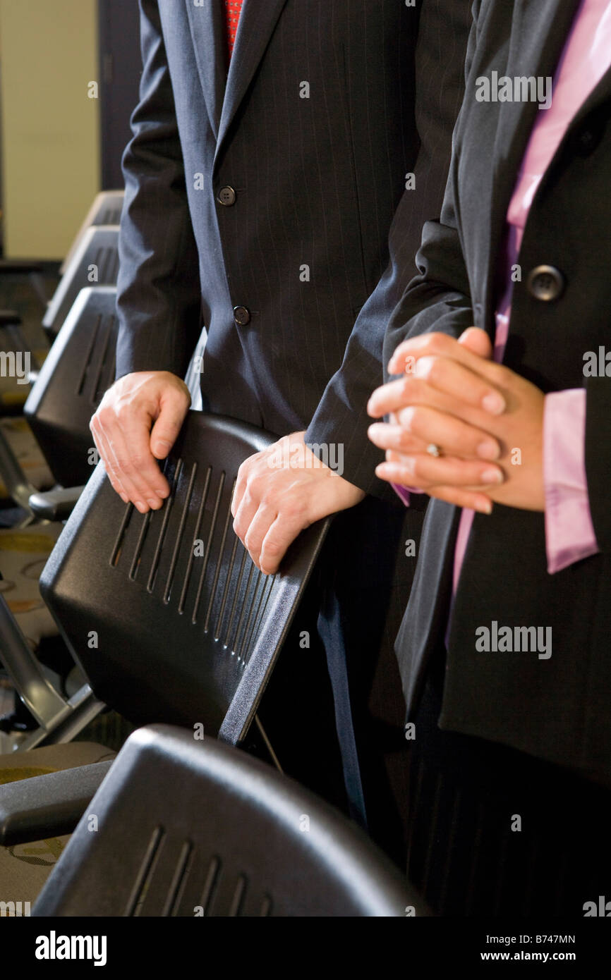 Mid section of two businesspeople standing by chairs in board room Stock Photo