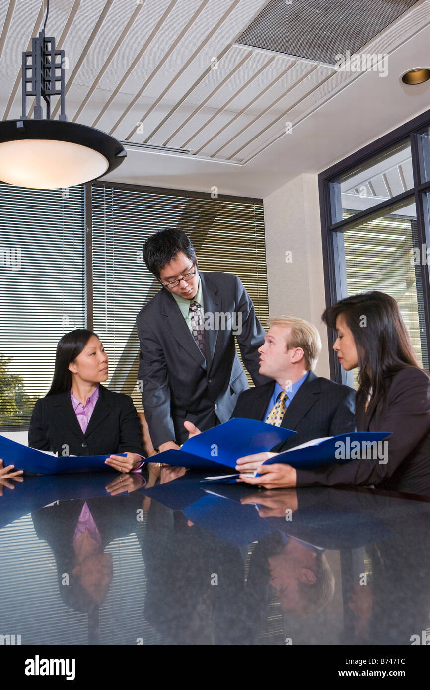 Caucasian businessman negotiating with Asian executives in boardroom Stock Photo