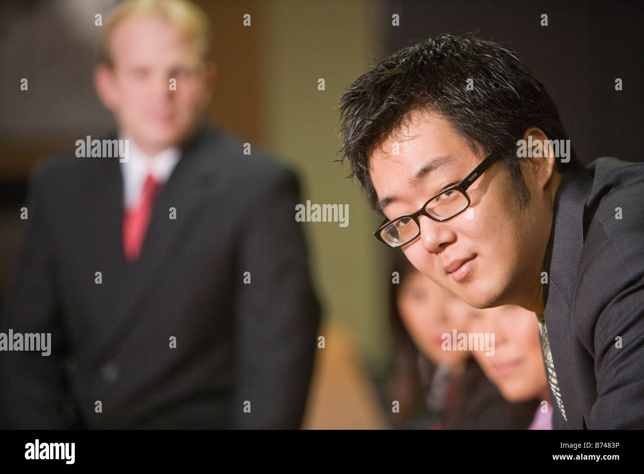 Four multi-ethnic businesspeople boardroom, focus on foreground Stock Photo