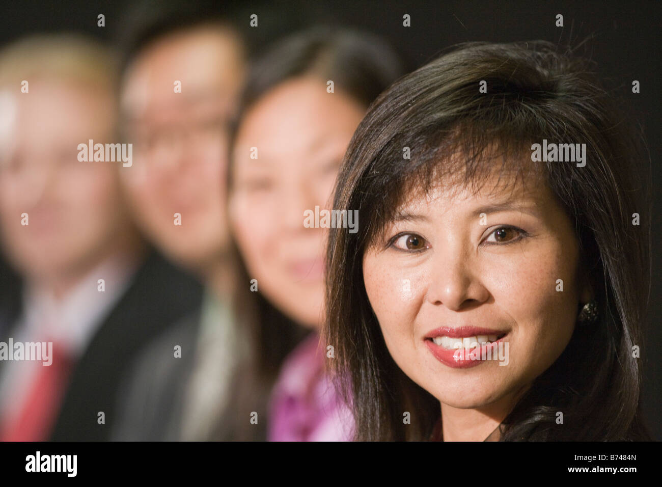 Close-up of businesspeople sitting in a row, focus on Asian woman Stock Photo