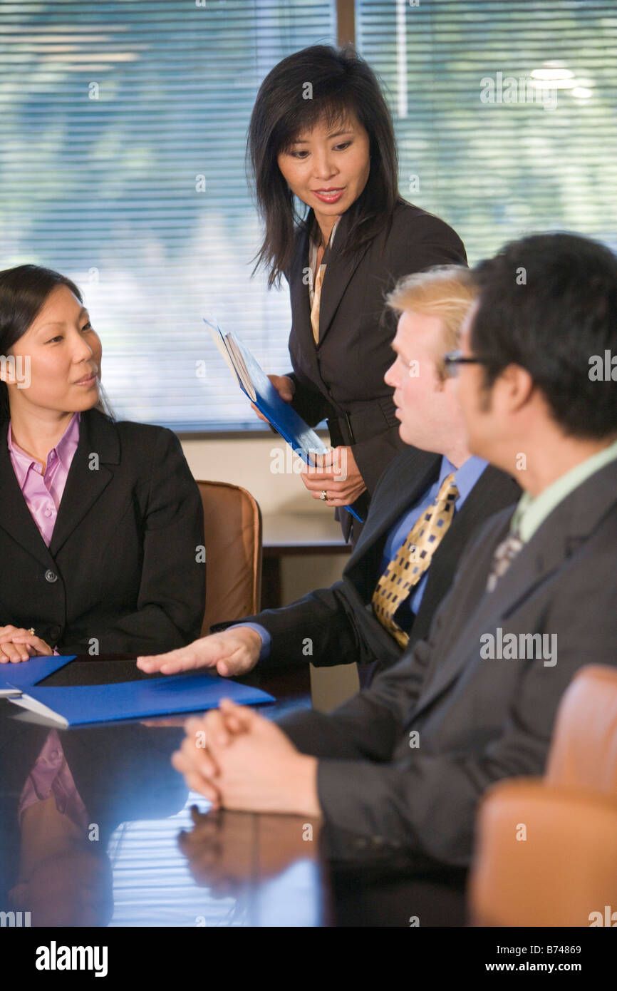 Caucasian businessman meeting with group of Asian executives in boardroom Stock Photo