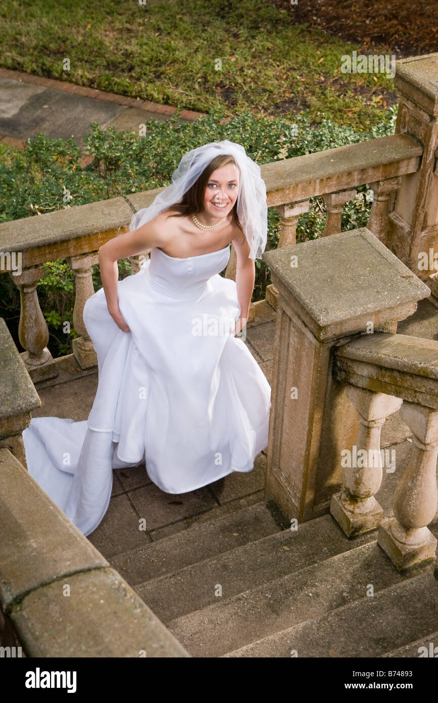 Happy young  bride  in wedding  dress  walking up stairs 