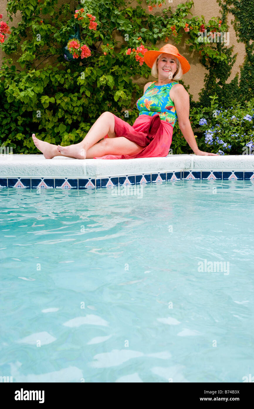 Mature woman sitting by the edge of swimming pool Stock Photo - Alamy