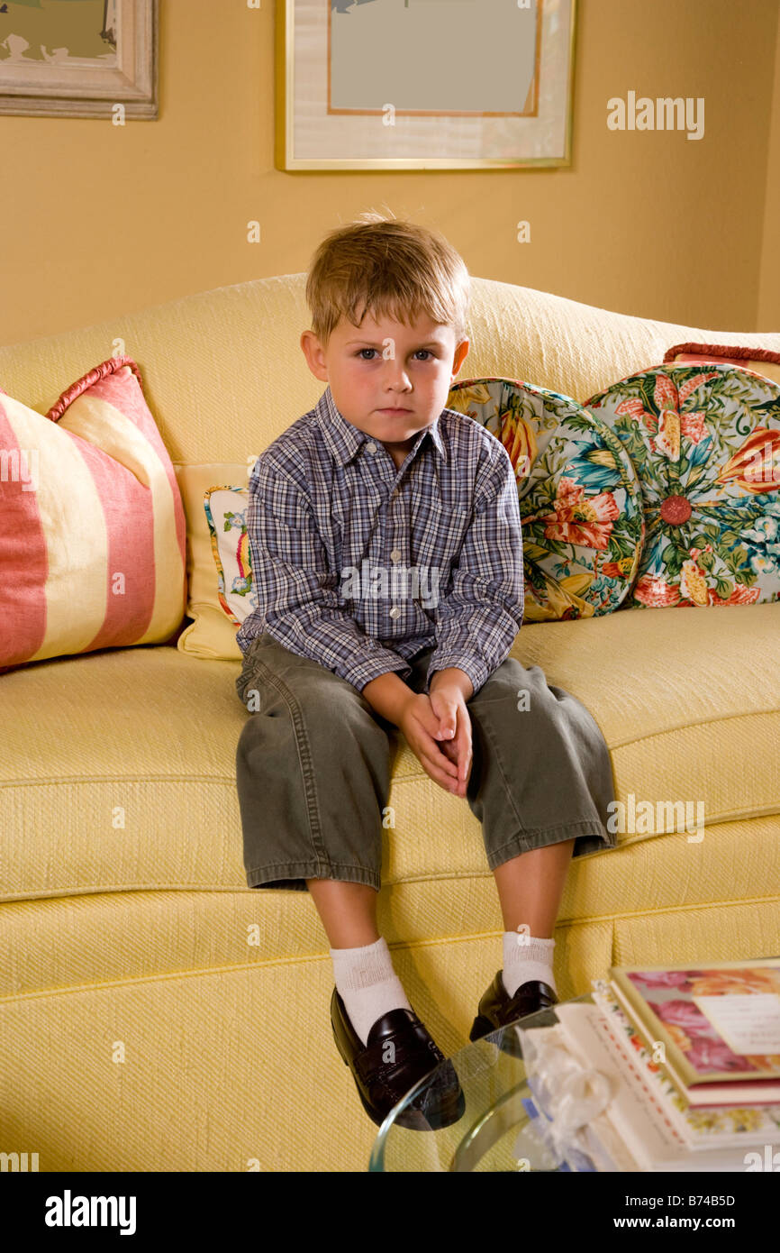 Portrait of serious young boy sitting on sofa Stock Photo - Alamy