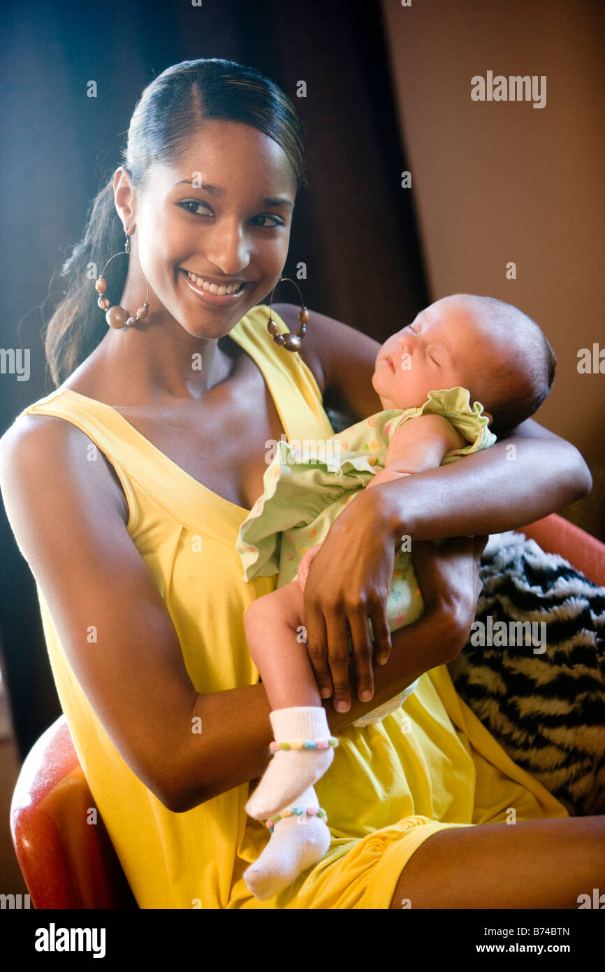 Young African American mother sitting on chair holding baby Stock Photo