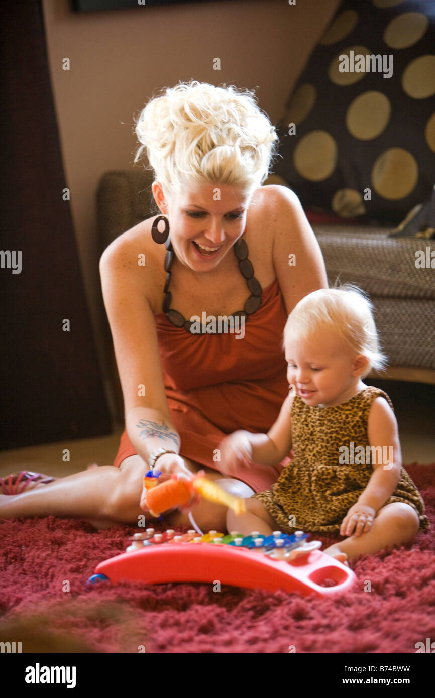 Young mother sitting on floor playing with baby girl Stock Photo - Alamy