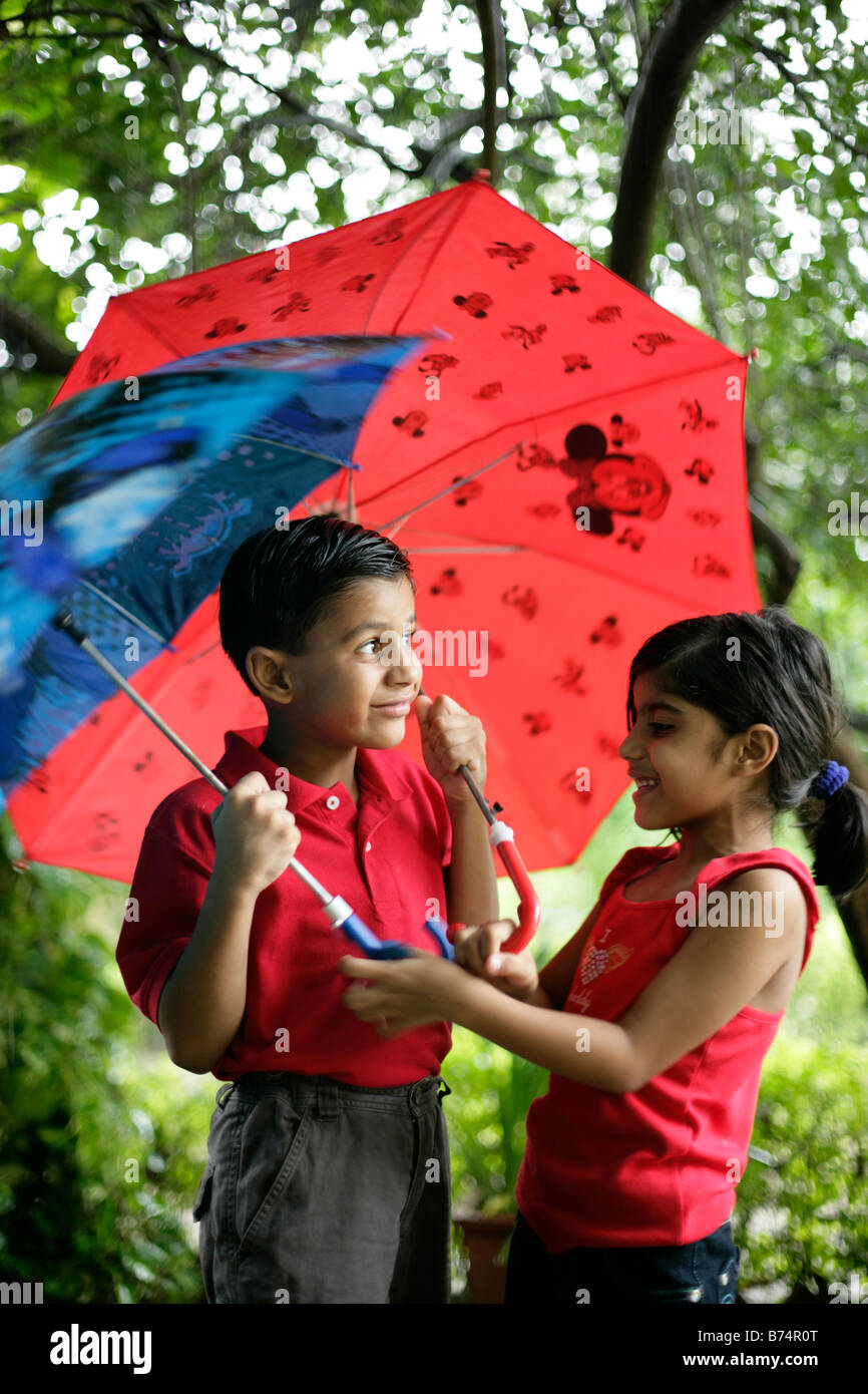 Mischievous kids in the rain slight motion blur trying to get the most colorful umbrella Stock Photo