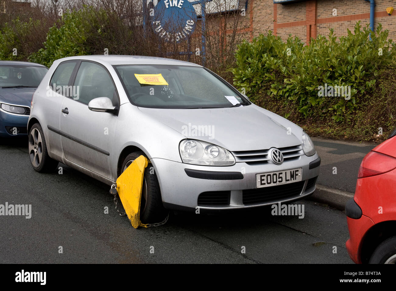 Wheel clamp on untaxed car with statutory notice attached to the windscreen. Stock Photo