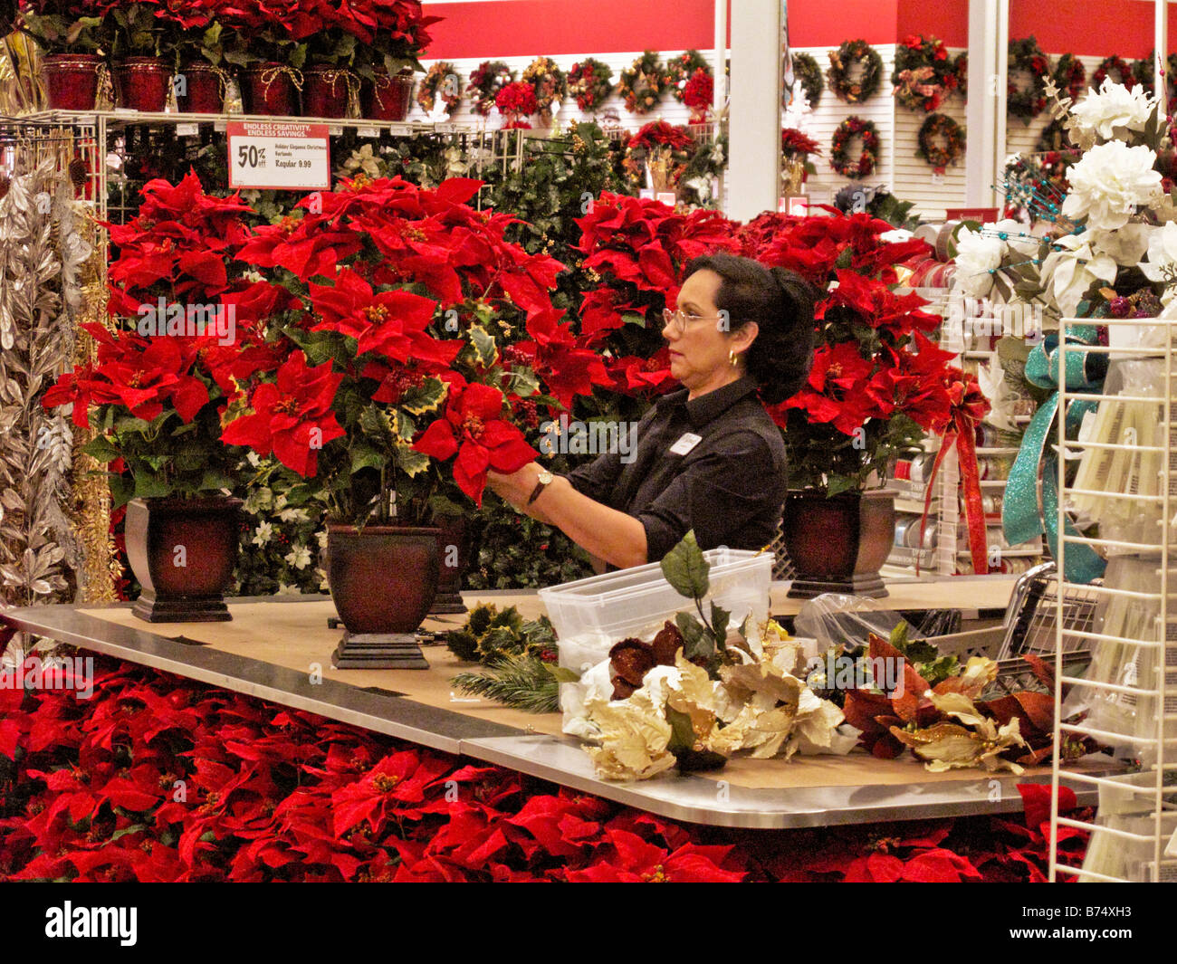 A gift store clerk assembles Christmas season artificial poinsettia bouquets in Aliso Viejo CA Stock Photo