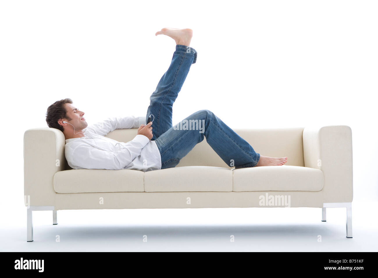 One mid adult man lying on sofa listening MP3 player Stock Photo - Alamy