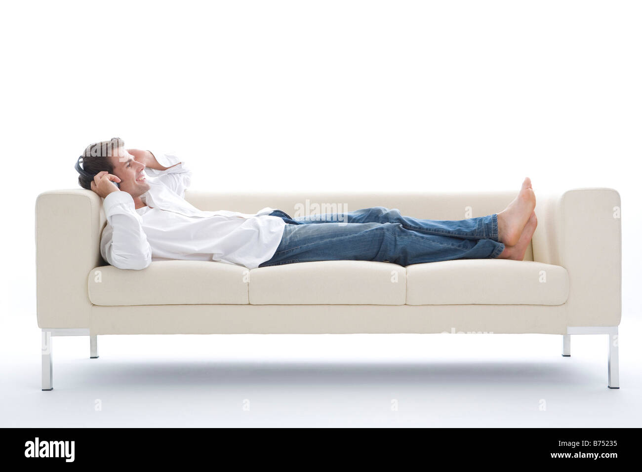 One mid adult man lying on sofa listening MP3 player Stock Photo - Alamy