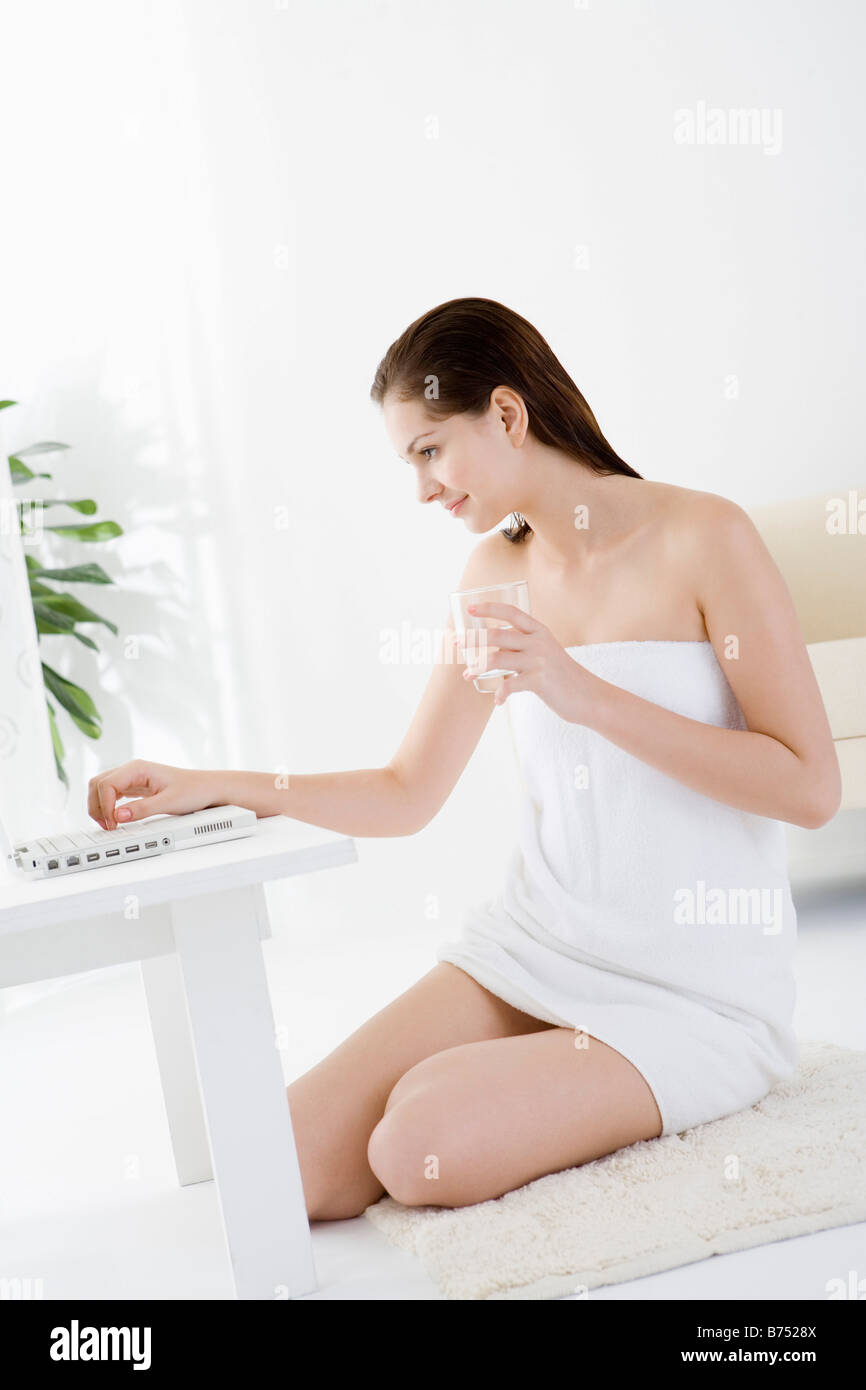 Teenage girl wrapped in towel sitting on rug using laptop Stock Photo ...